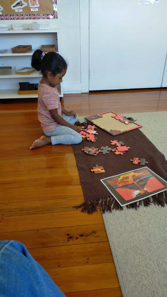 a young child sits on a mat and does a jigsaw at Tipu Montessori school